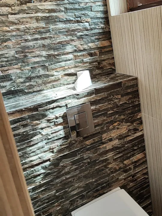 Toilette terminée avec parement en pierre et plaque de commande encastrée