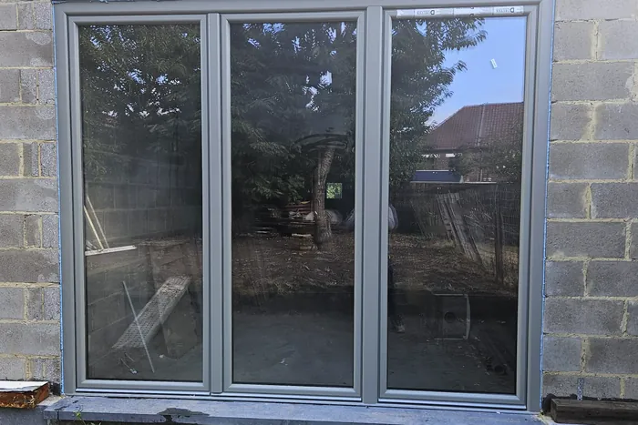 Baie vitrée à trois vantaux posée dans une façade en cours de construction