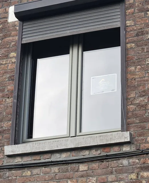 Châssis à deux vantaux surmonté d'un volet roulant dans une façade en briques