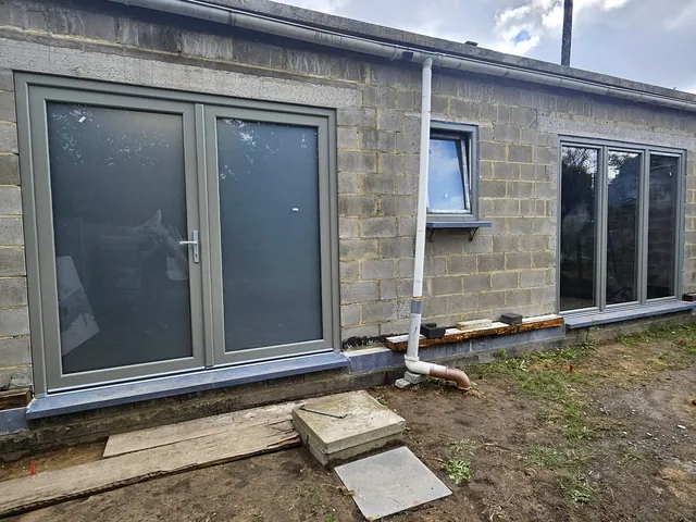 Façade arrière en blocs avec porte-fenêtre et châssis gris posés