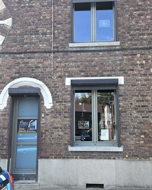 Façade en briques avec nouveaux châssis gris et porte d'entrée