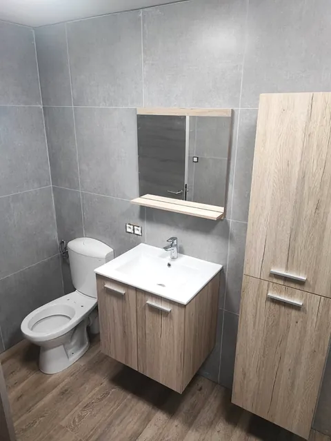 Salle d'eau carrelée avec meuble vasque, colonne de rangement et WC