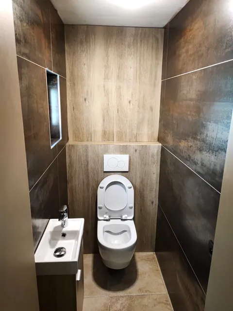 WC suspendu dans un espace entièrement carrelé avec niche murale